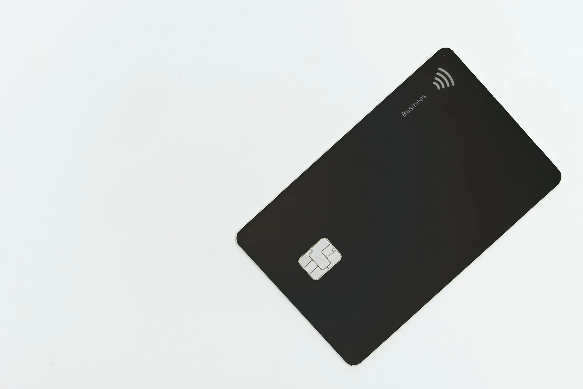 A dark contactless card with a chip on a white surface.