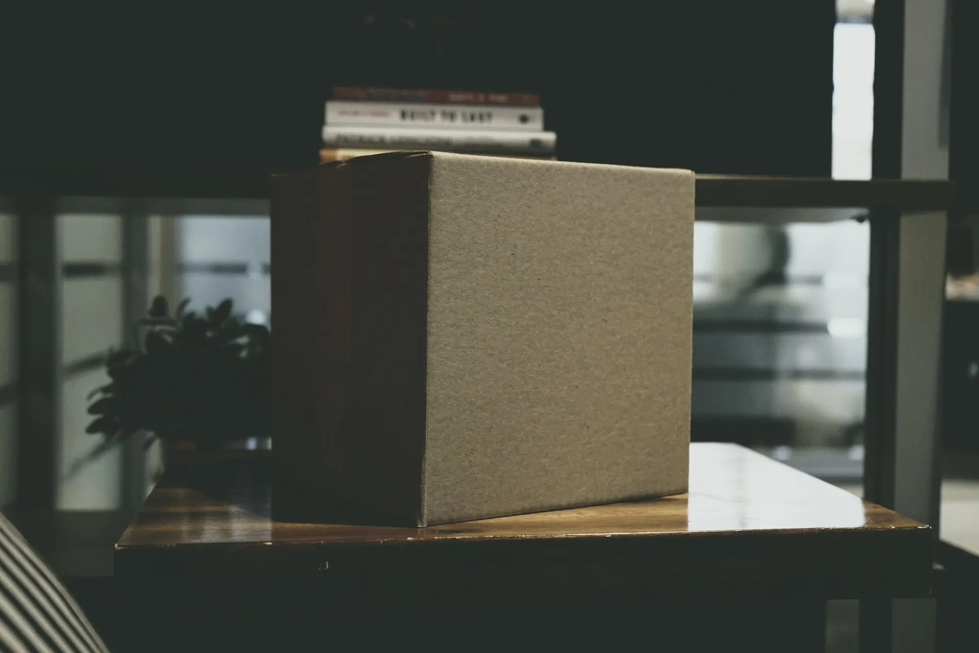 A plain cardboard delivery box on a wooden table indoors.