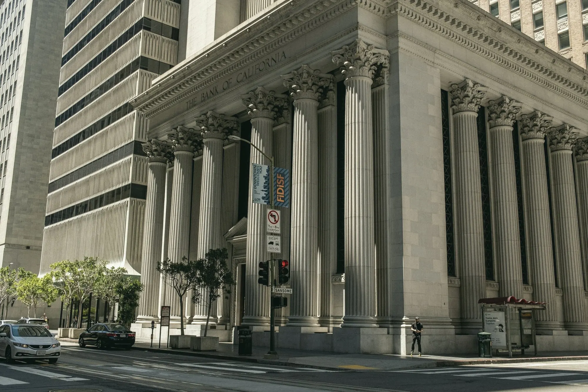 A stone bank-style building with tall columns on a city street.
