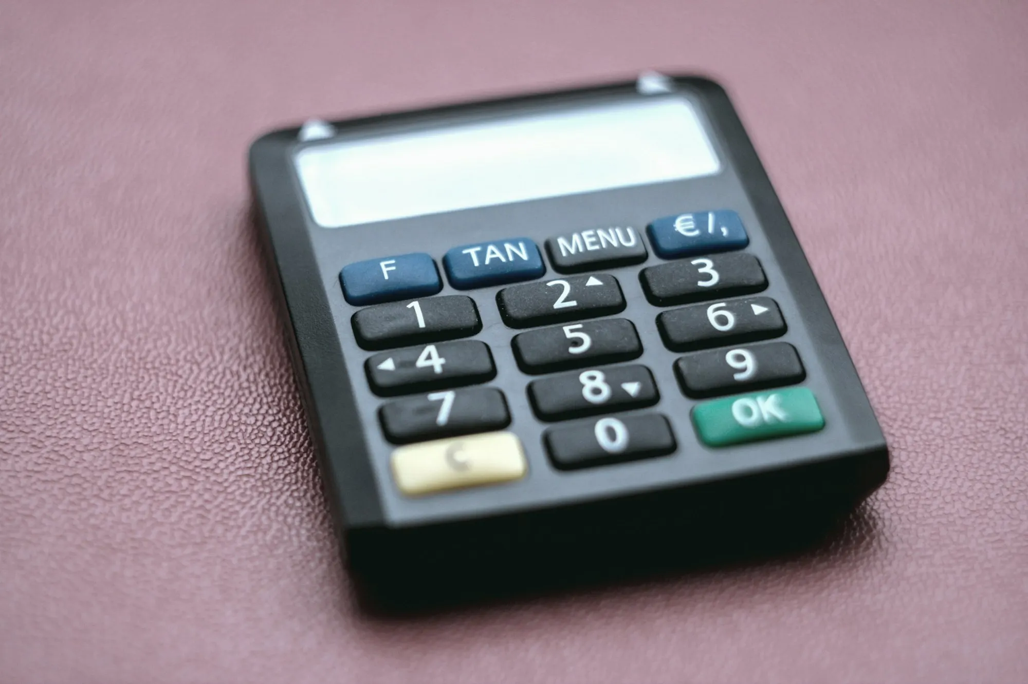 A black card reader with a numeric keypad on a red surface.