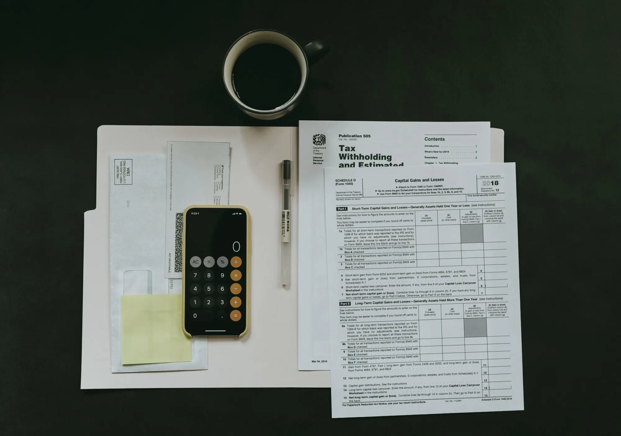 Paper forms, a calculator on a phone, and a pen laid out beside a coffee cup.