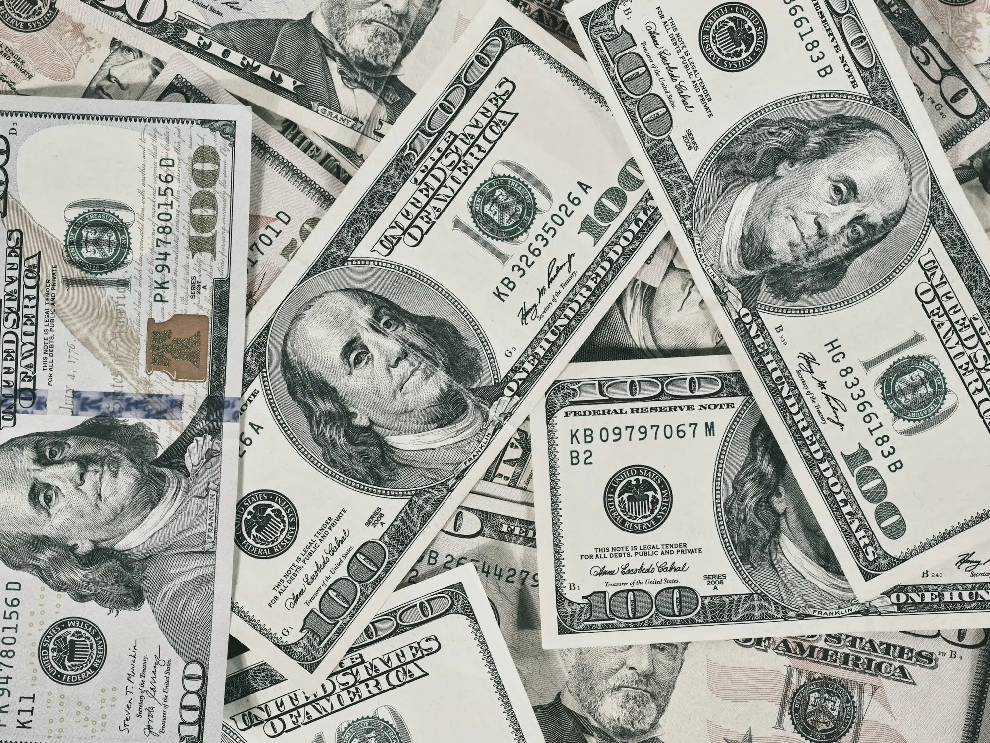 A loose pile of US hundred and fifty dollar bills scattered across a flat surface.