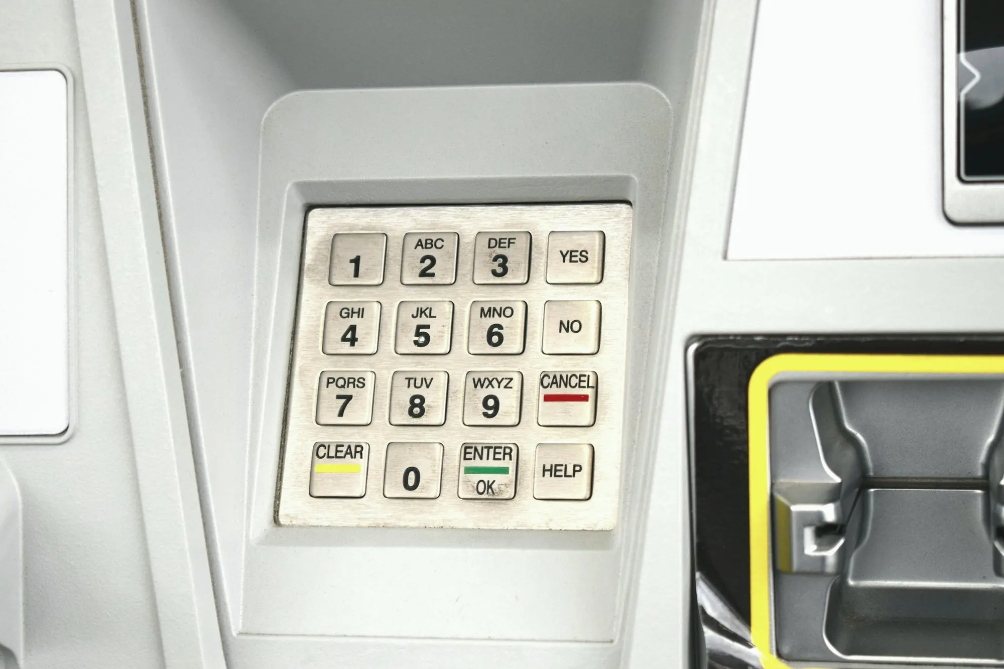 Close-up of a metal ATM keypad with numbered keys beside the card slot.